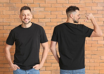 man wearing plain black tee shirt in front of brick wall